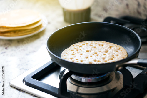 Making american pancakes on frying pan in kitchen interior