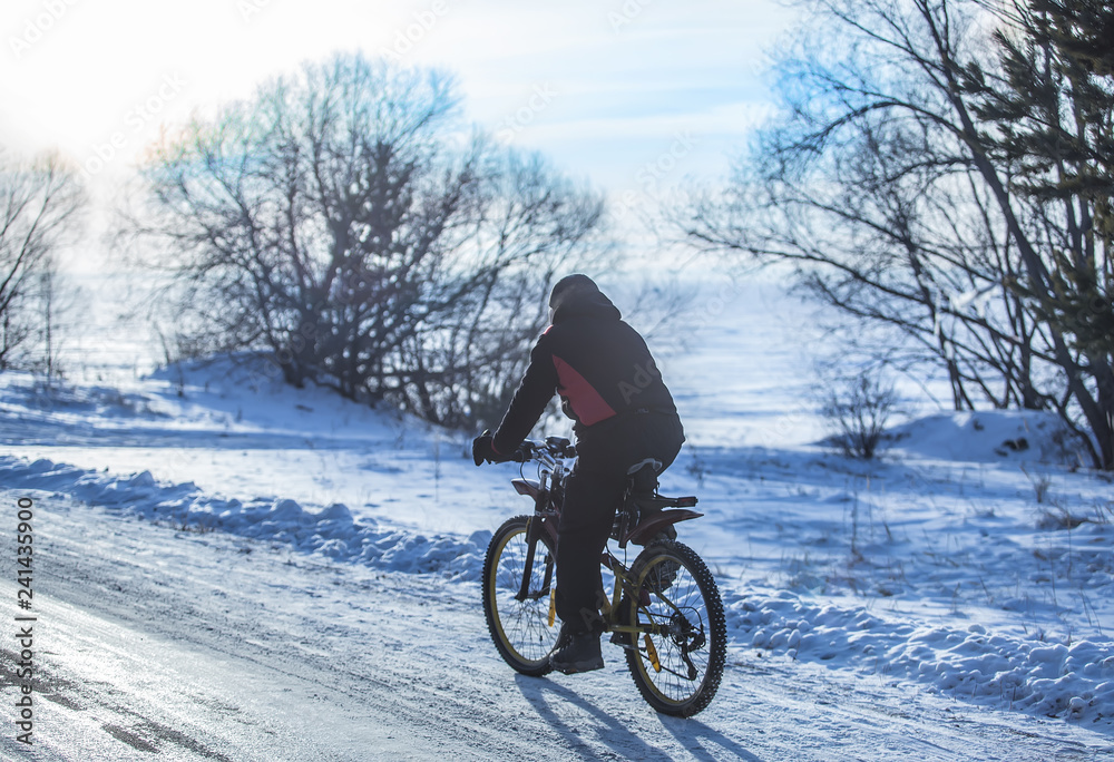 Cyclist on a bike rides in the winter on road