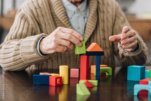 cropped view of senior man playing with wooden toys at home
