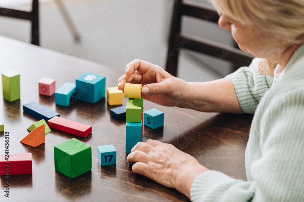 senior woman playing with wooden cubes on table senior woman playing with wooden cubes on table