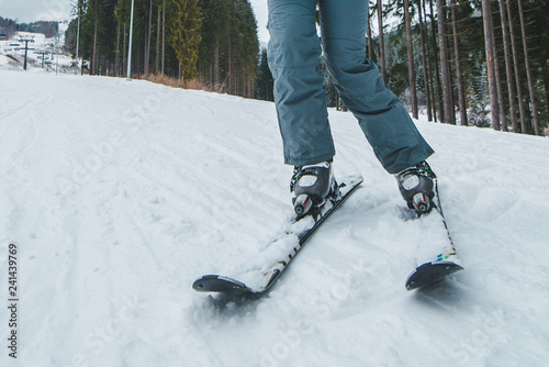 woman legs ski close up. snowed hill on background with lift