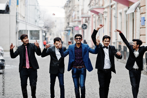 Group of 5 indian students in suits posed outdoor, having fun and dancing.