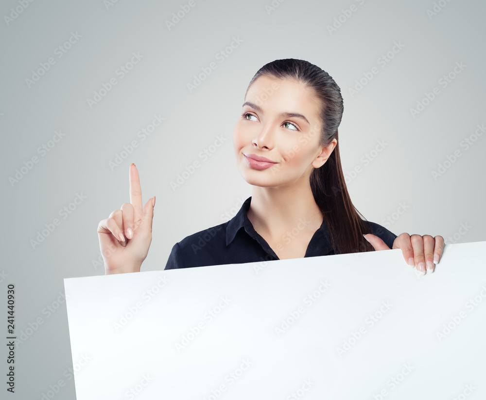 Smiling businesswoman pointing up and showing empty paper signboard Smiling businesswoman pointing up and showing empty paper signboard
