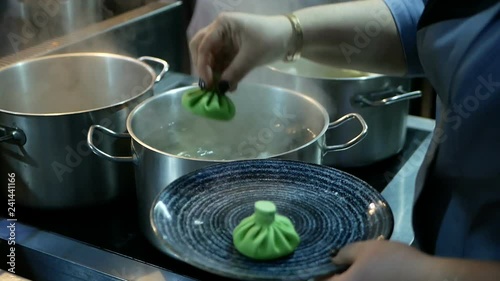 The cook prepares the Georgian national food of Khinkali. Green khinkali with salmon, spinach, cheese and cream. Boil in the pan meat in the dough.