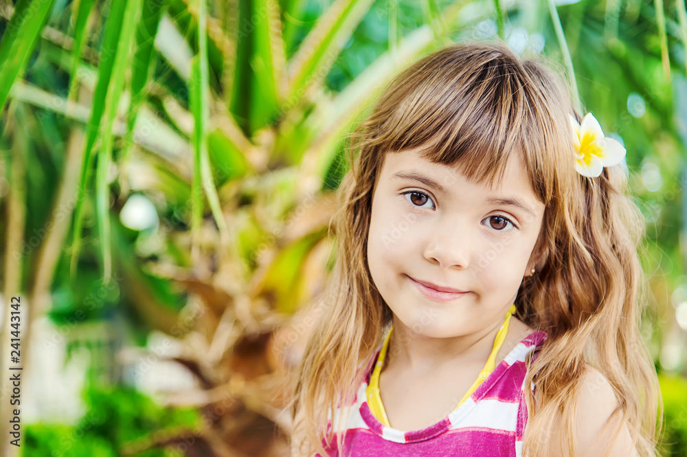 girl with a plumeria flower in her hair against the backdrop of palm