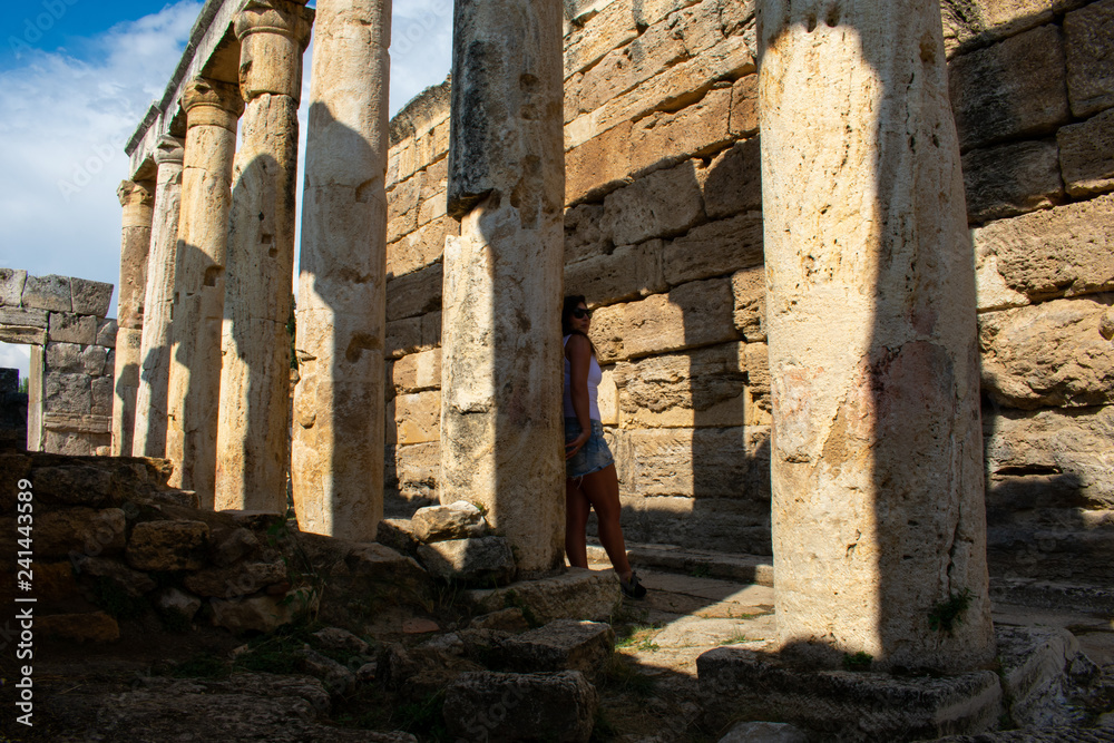 Fototapeta premium Beautiful Young woman with dark hair posing in Old ancient ruins of roman City Hierapolis in Pamukkale, Turkey 