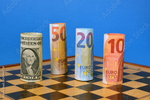 Three Euros banknotes challenge one american dollar on a chessboard. photo