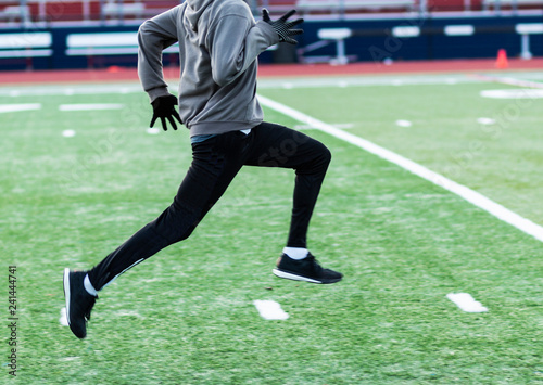 Φωτογραφία Runner sprinting on green turf field in the cold