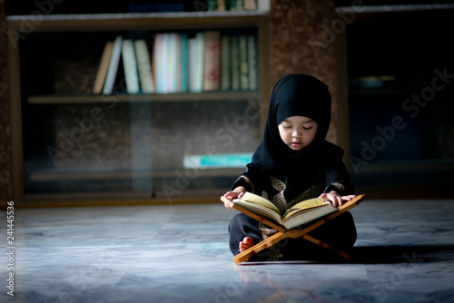 Asian Indonesian Muslim kid is reading the Quran. The Quran is indicated as the guided book for all Muslim and it is direction  to be on the heaven of God.Mosque,Islam,religion and knowledge concept. photo