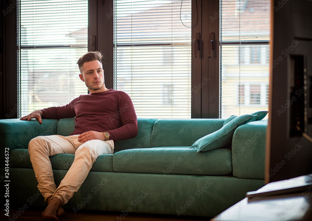 Young man sitting watching television changing the channel with the remote control