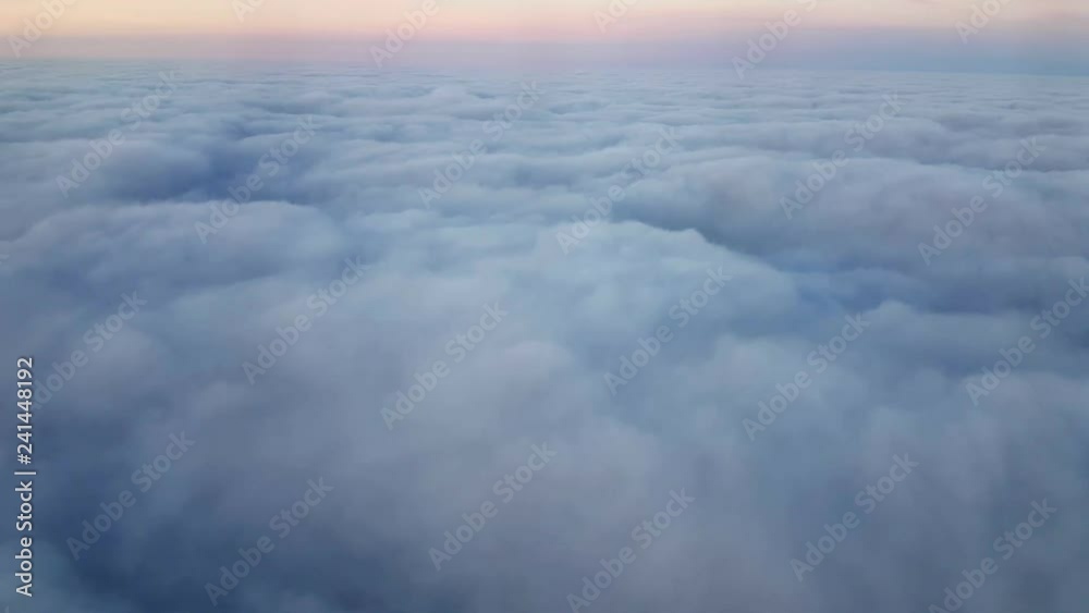 Aerial shot of fuzzy clouds with a violet horizon from a plane window at sunset Aerial shot of fuzzy clouds with a violet horizon from a plane window at sunset