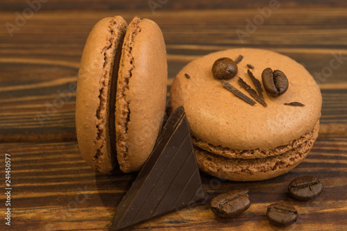 Chocolate almond macaroons with coffee beans, on a dark wooden table. Sweet macaroons with a piece of chocolate. Top view