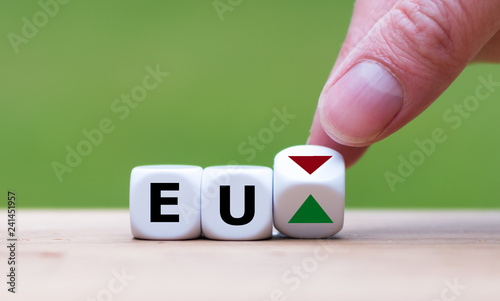 Hand is turning a dice and changes the direction of an arrow symbolizing that European economy is changing the trend and goes up instead of down (or vice versa)