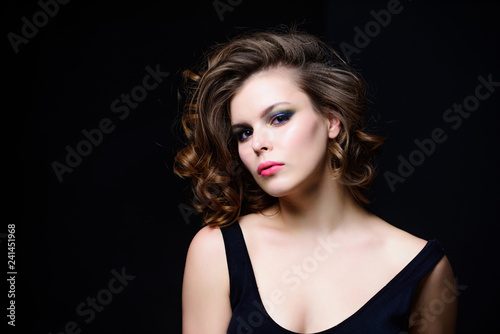 Makeup idea for elegant outfit. Attractive elegant lady with smoky eyes makeup and pink lipstick. Professional makeup. Beauty salon concept. Woman with curly hairstyle and makeup on black background