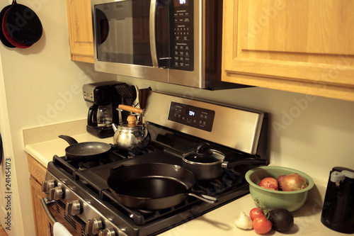 Modern stainless steel gas stove oven with cookware in a home.