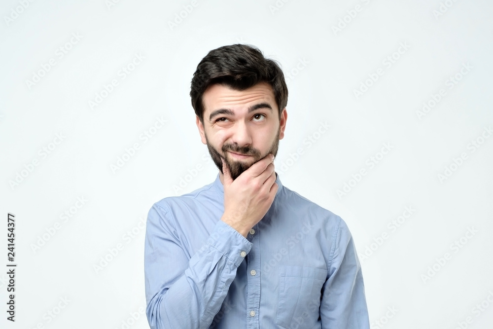 Pensive spanish man in blue shirt against a white background Pensive spanish man in blue shirt against a white background