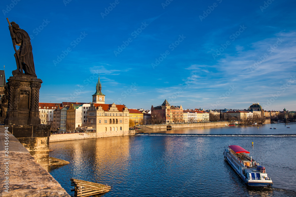Boat navigating on Vlava river at sunset in Prague