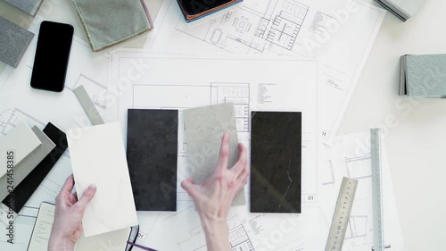 The interior designer selects ceramic stoneware and marble samples. Designer at work. Interior design. Architecture. Decoration. Design project blueprints. Grey marble. Grey stone. Decorative material