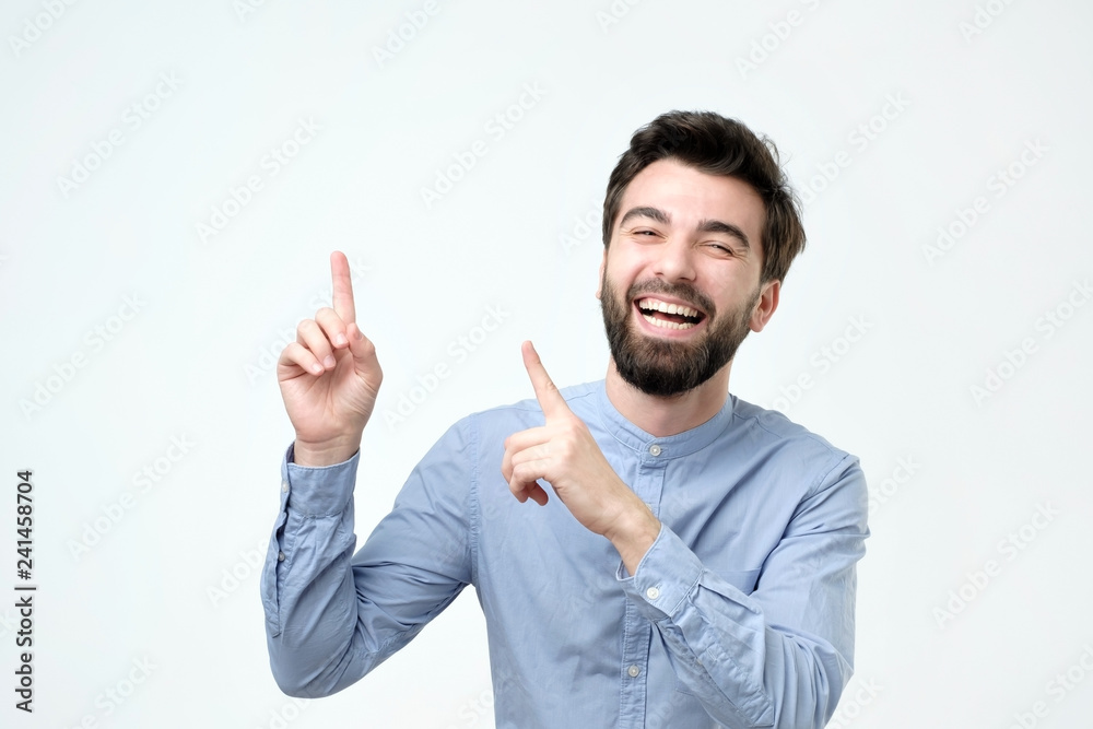 an smiling with happy face looking and pointing to the side with finger an smiling with happy face looking and pointing to the side with finger