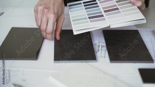 The interior designer selects ceramic stoneware and marble samples. Designer at work. Interior design. Architecture. Decoration. Design project blueprints. Grey marble. Grey stone. Decorative material