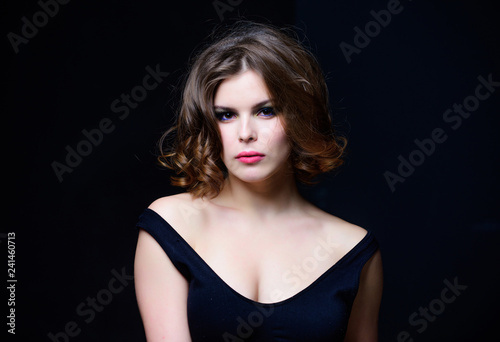 Woman with curly hairstyle and makeup on black background. Makeup idea for elegant outfit. Attractive elegant lady with smoky eyes makeup and pink lipstick. Professional makeup. Beauty salon concept