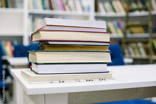 Book stack in the library room and blurred bookshelf for business and education background, back to school concept