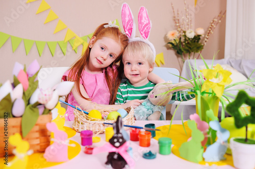 children - a little boy and a girl are preparing for the celebration of Easter. Brother and sister paint eggs on the background of the Easter decor