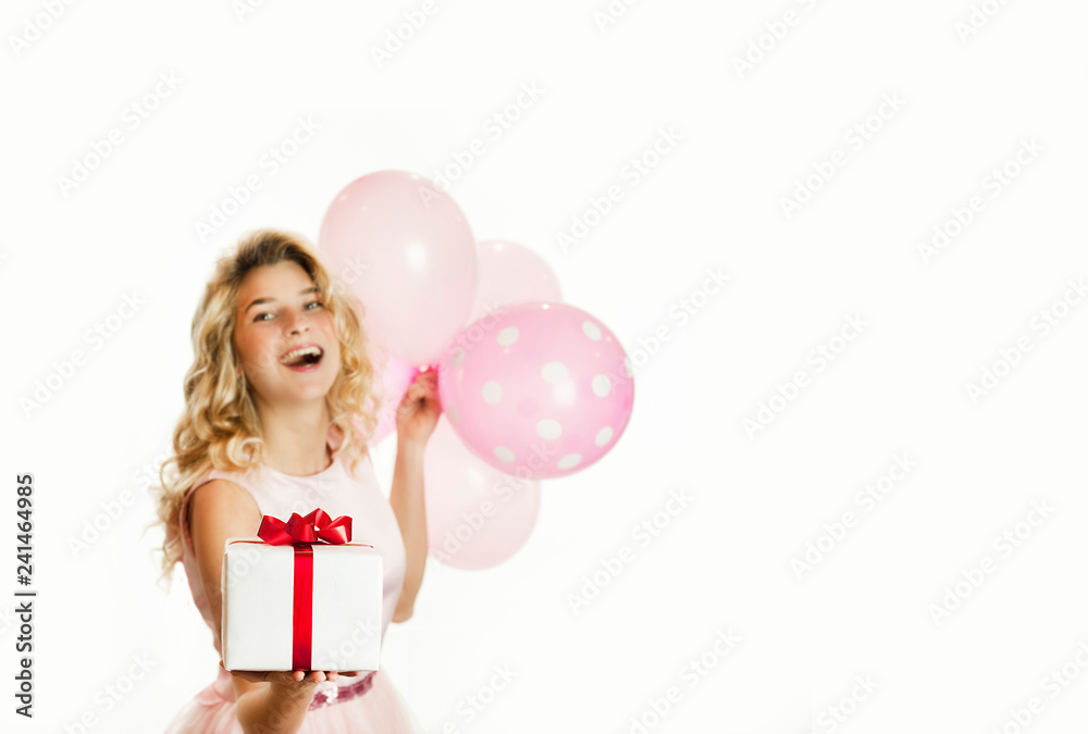 Young beautiful girl with a white gift with a red bow and balls in the hands rejoices on an isolated white background. Valentine day concept. Young beautiful girl with a white gift with a red bow and balls in the hands rejoices on an isolated white background. Valentine day concept.
