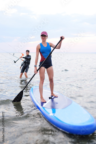 attractive young girl with SUP board on the background of the sea and sunset