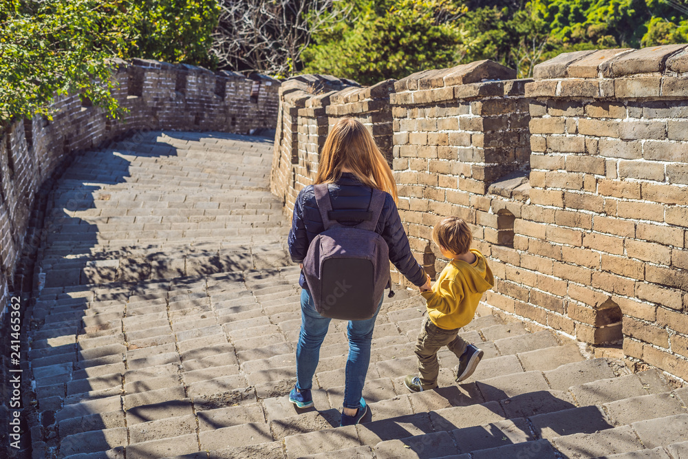 Fototapeta premium Happy cheerful joyful tourists mom and son at Great Wall of China having fun on travel smiling laughing and dancing during vacation trip in Asia. Chinese destination. Travel with children in China