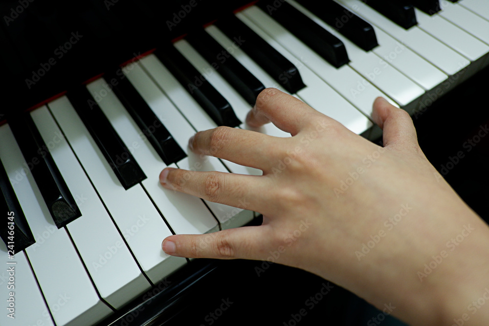 Fototapeta premium close-up female hand playing grand piano.