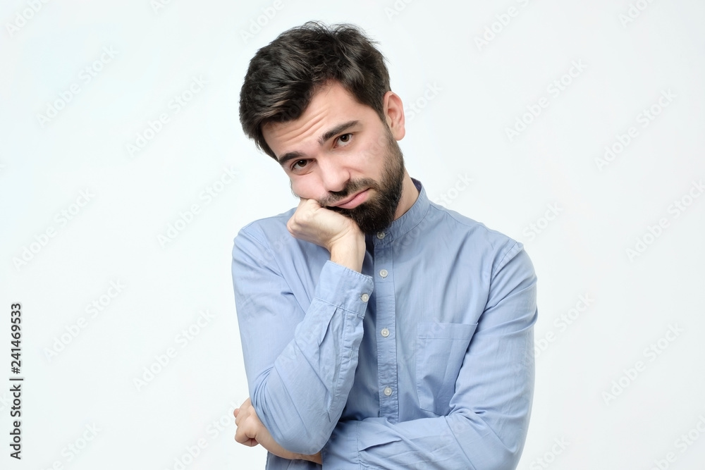 Man with beard holding hand on cheek looking tired and sick Man with beard holding hand on cheek looking tired and sick