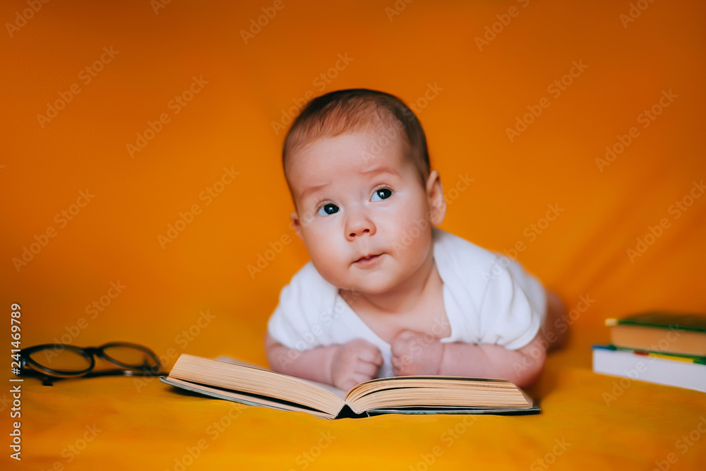 Adorable 3 months old baby looking and reading a book. Happy child playing and discovery. Early development, learning and education of kid Adorable 3 months old baby looking and reading a book. Happy child playing and discovery. Early development, learning and education of kid