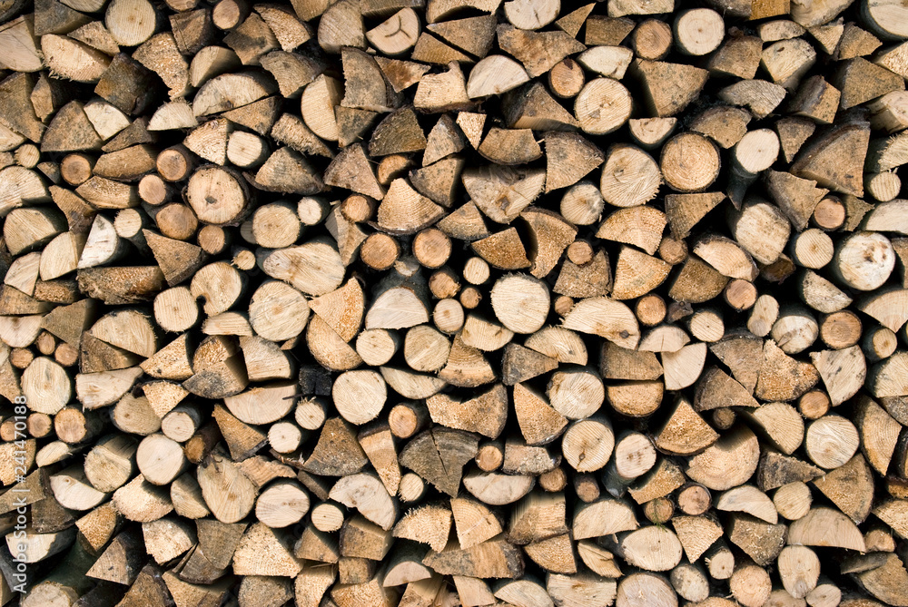 Stacked firewood for the heating season. Firewood stack wall. Wood texture background.