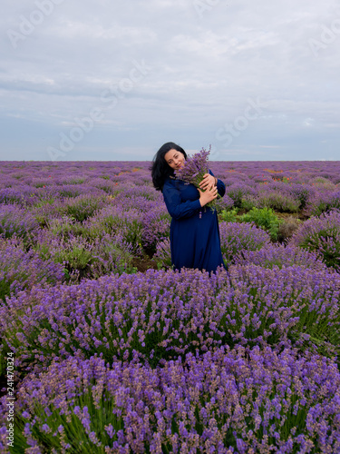 Young girl with a bouquet in hands, posing in a lavender field.