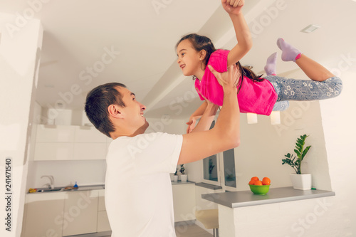 Happy family. Young father playing silly with his daughter lifting her up