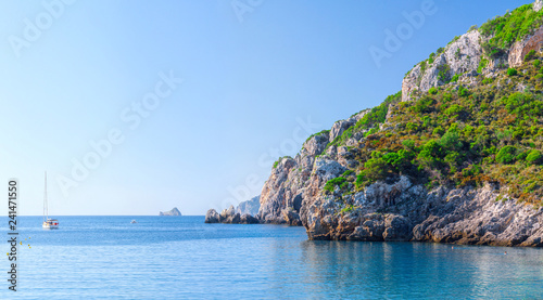 Beautiful summer panoramic seascape. View of the cliff into the sea bay with crystal clear azure water in sunshine daylight. Boats and yachts in the harbor. Mediterranean sea  somewhere in Europe.