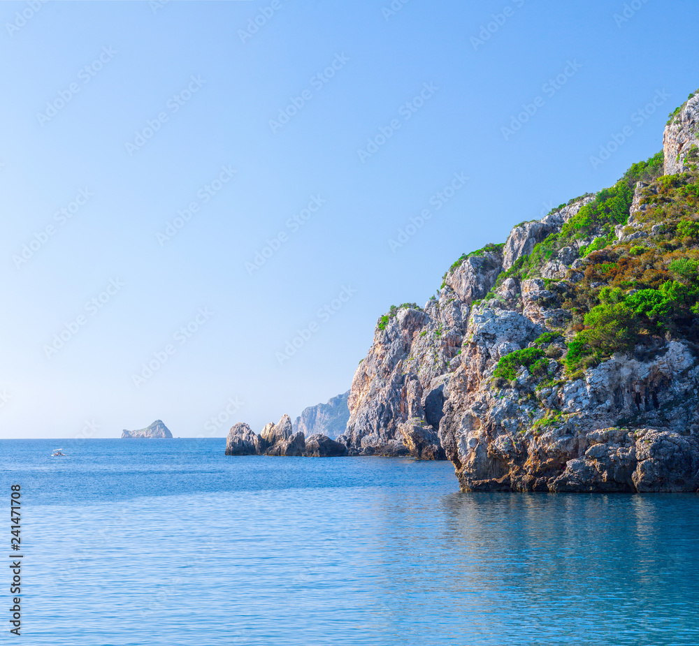 Beautiful summer panoramic seascape. View of the cliff into the sea bay with crystal clear azure water in sunshine daylight. Boats and yachts in the harbor. Mediterranean sea, somewhere in Europe.