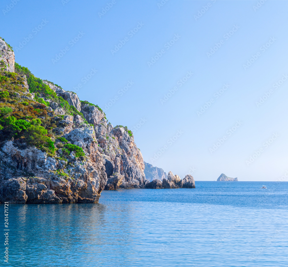 Beautiful summer panoramic seascape. View of the cliff into the sea bay with crystal clear azure water in sunshine daylight. Boats and yachts in the harbor. Mediterranean sea, somewhere in Europe.