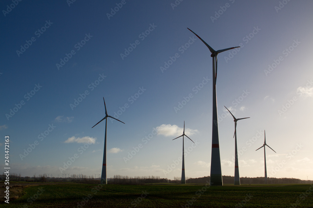 wind turbine silhouettes with blue sky in the background