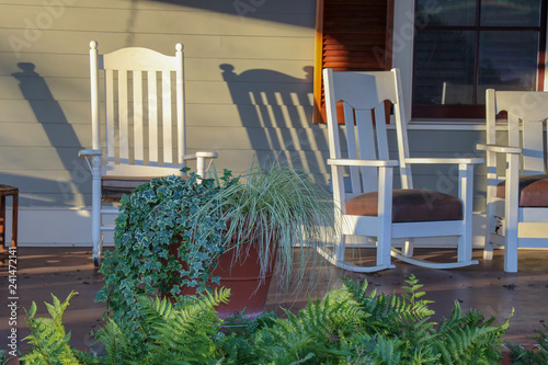 white rocking chairs on a front porch in afternoon or morning sun invite relaxation