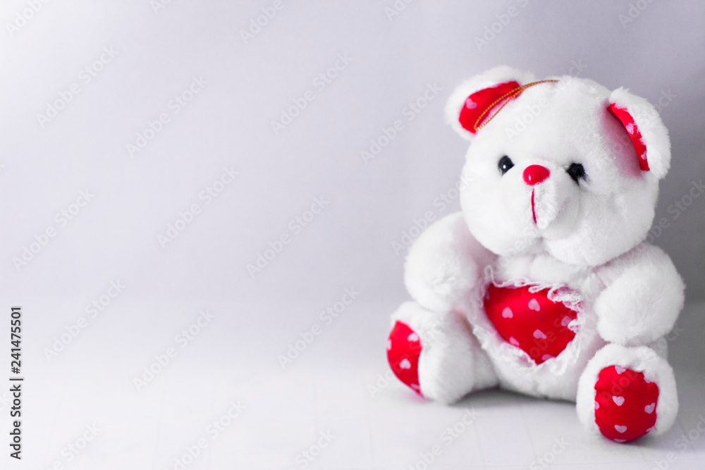 White Teddy Bear with red heart sitting on white background. Toys for children concept. Valentine's day background. Gift for woman or child.