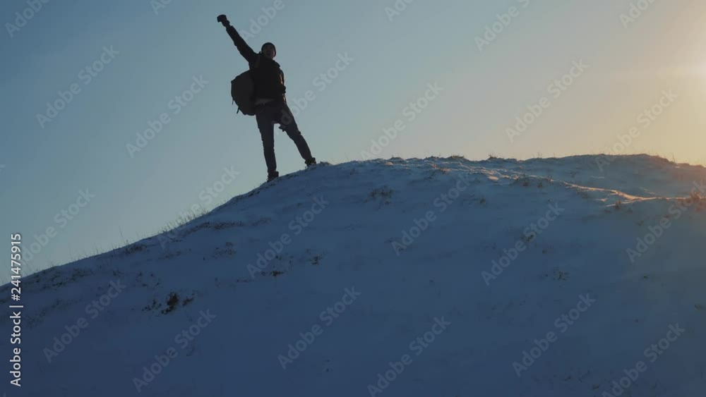 success victory win business travel concept. man rock climber tourist rejoices jumping on top of a mountain snow winter. overcoming the difficulties of the problem, the tourist rises to the top of the success victory win business travel concept. man rock climber tourist rejoices jumping on top of a mountain snow winter. overcoming the difficulties of the problem, the tourist rises to the top of the
