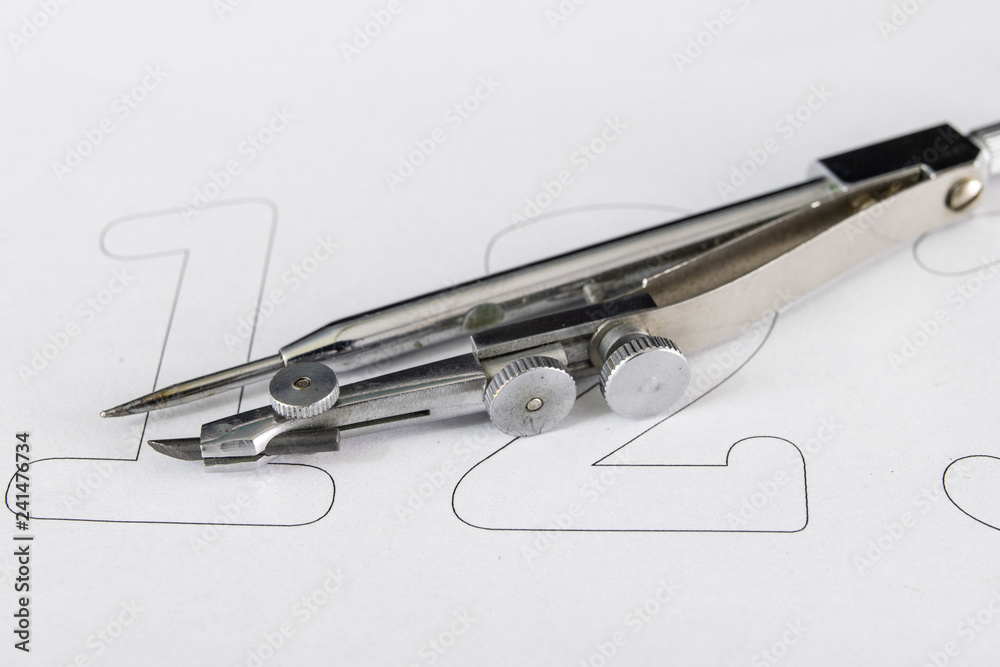 Fototapeta premium A companion for drawing circles on a white piece of paper. Drafting accessories for drawing technical drawings.