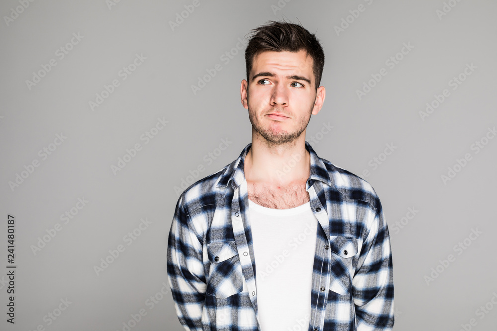 Close up portrait of a young man with a confused, thinking face isolated on gray background Close up portrait of a young man with a confused, thinking face isolated on gray background
