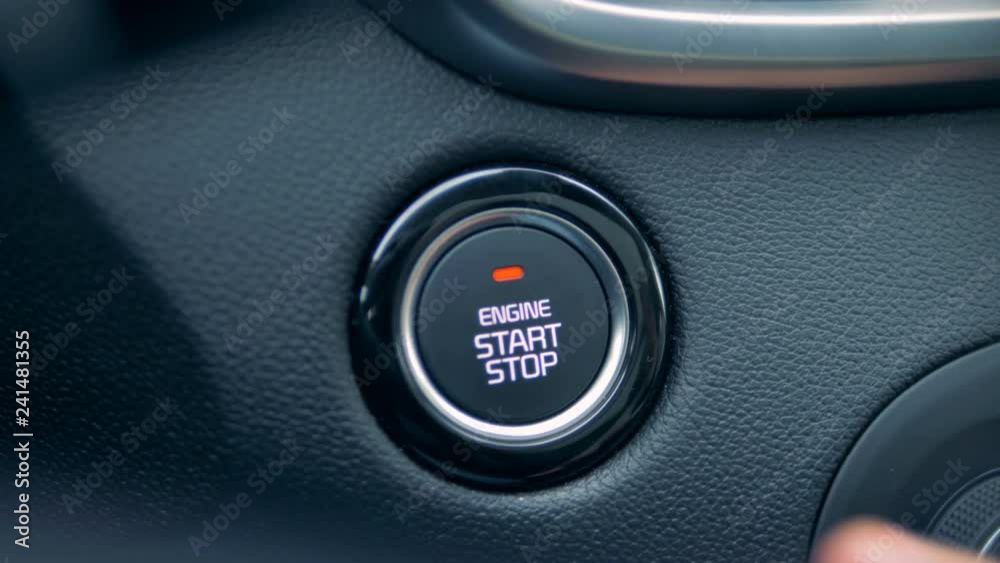 One man pressing start button in a car, close up. One man pressing start button in a car, close up.
