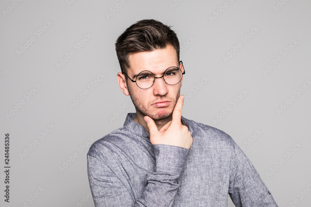 Handsome young man in eyesglasses standing and looking up isolated on the gray background Handsome young man in eyesglasses standing and looking up isolated on the gray background