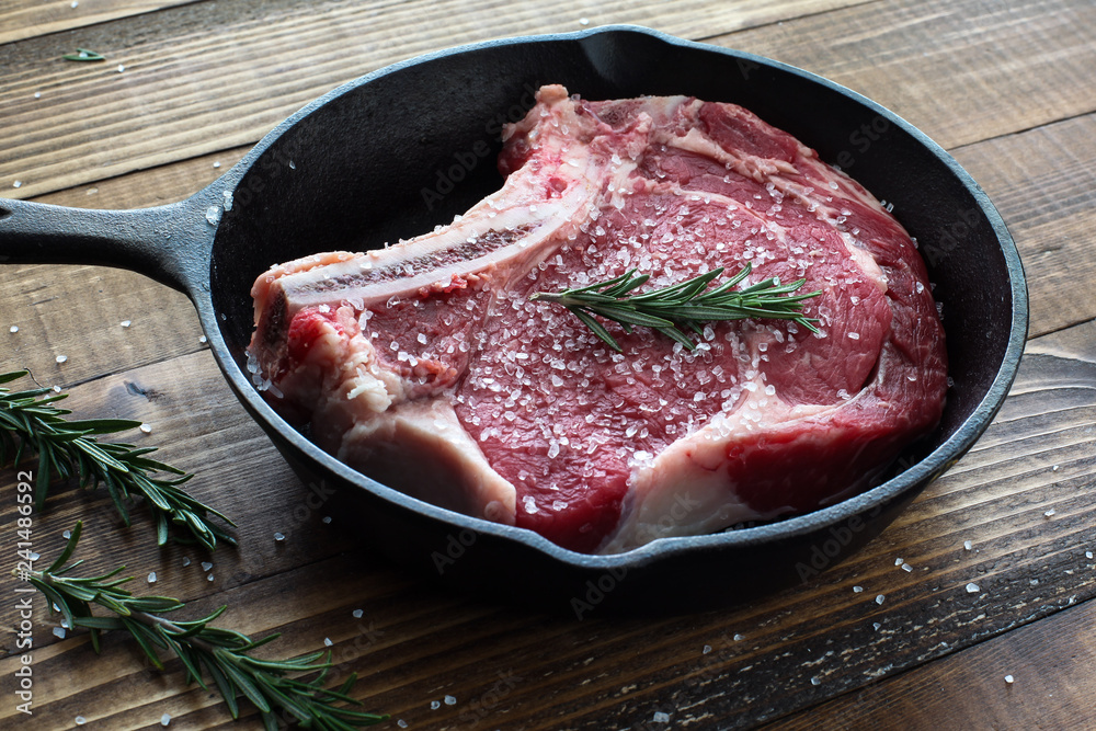 Beef steak bone in inside iron skillet with rosemary and sea salt Beef steak bone in inside iron skillet with rosemary and sea salt