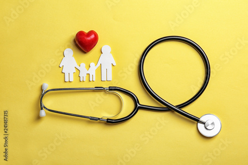 Flat lay composition with heart, stethoscope and paper silhouette of family on color background. Life insurance concept photo