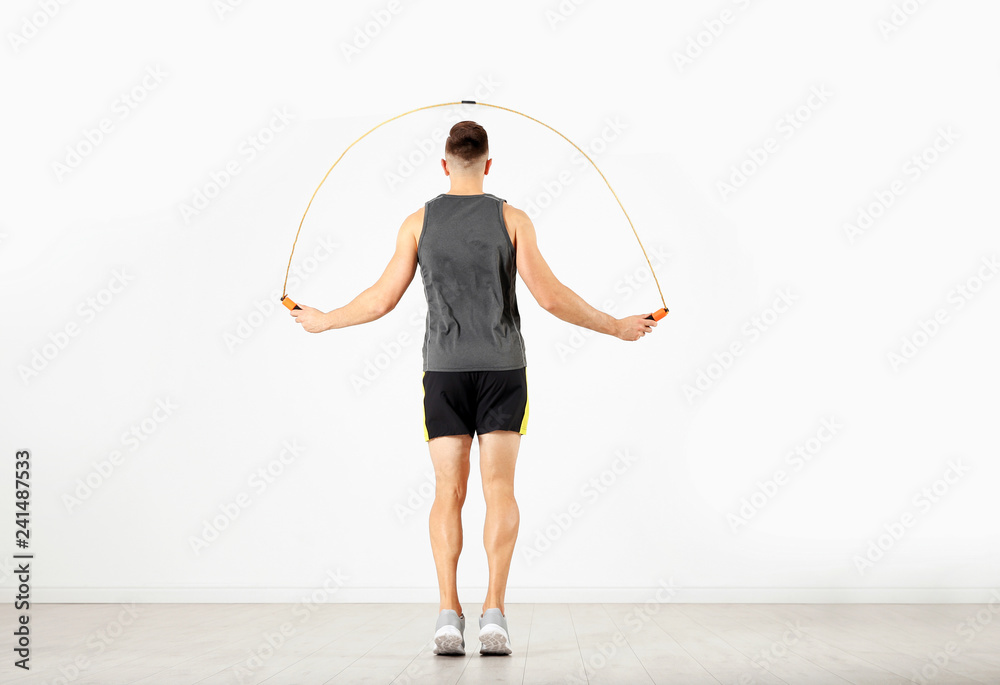 Sportive man training with jump rope in light room Sportive man training with jump rope in light room